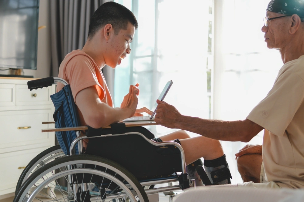 Disabled boy on wheelchair talking to friend on video call