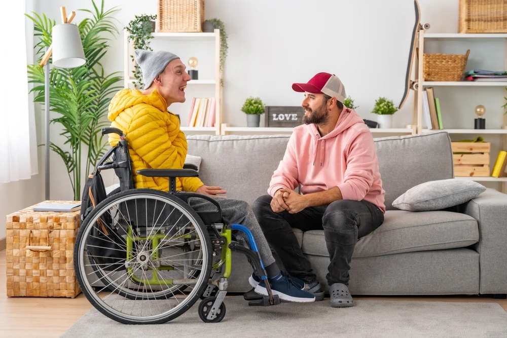 Disabled boy with down syndrome looking at carer and smiling
